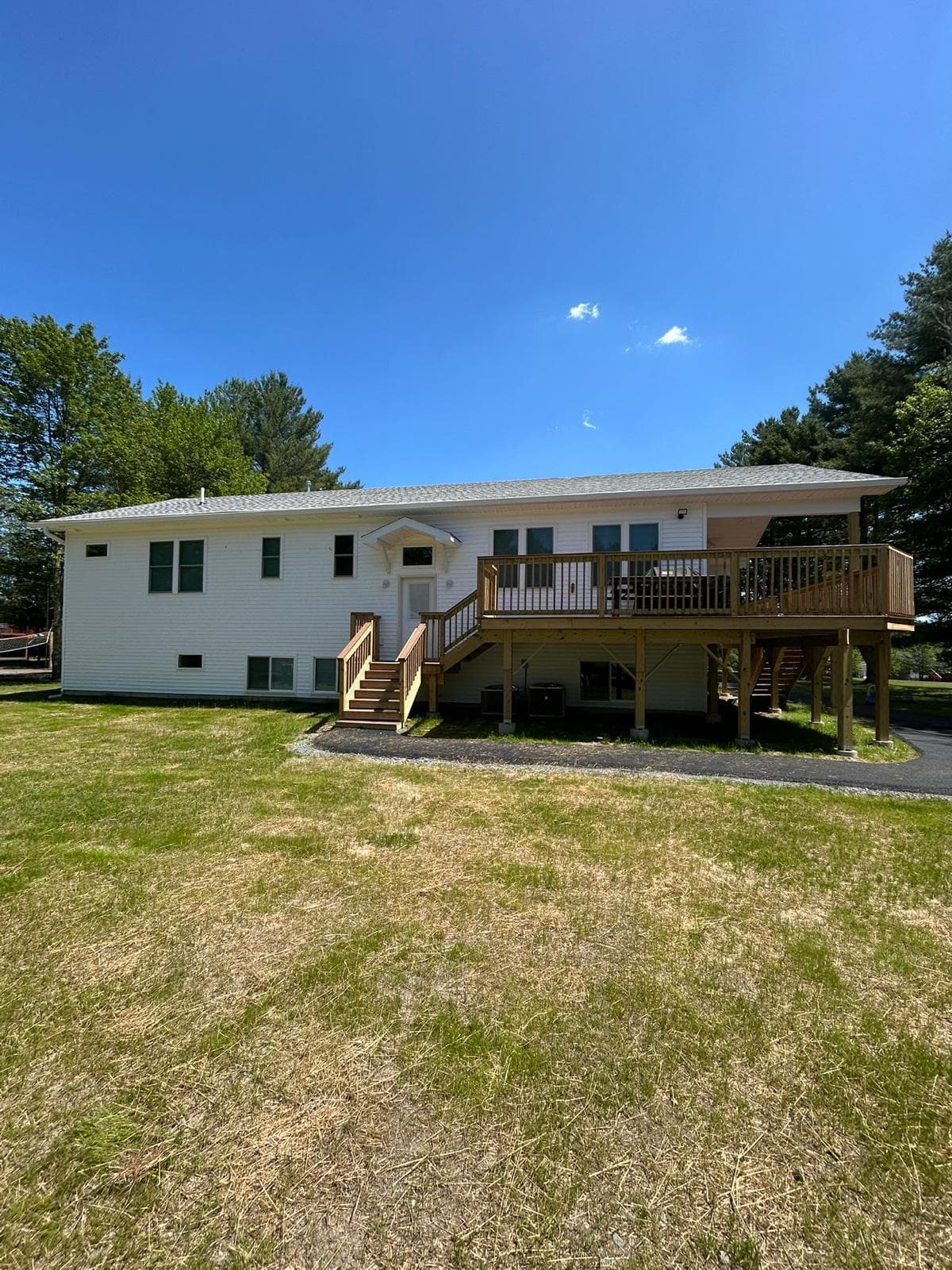 A white campus building seen across mown ground, a full-length raised deck and exterior stair running the length of the elevation