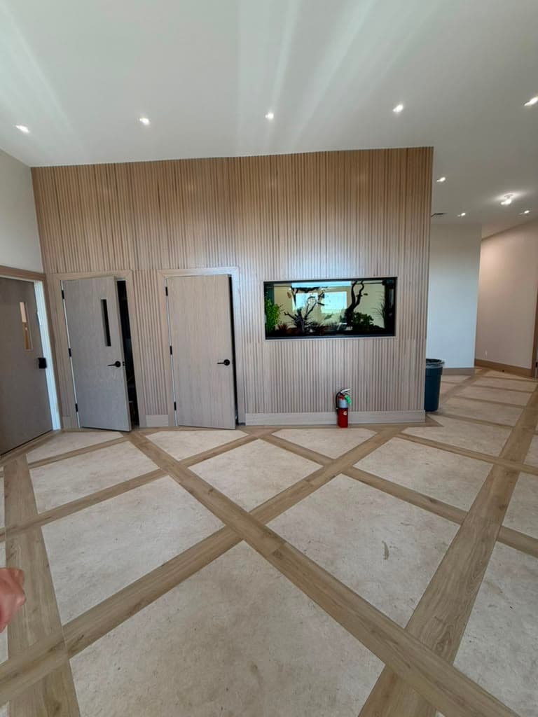 A double-height entrance hall finished in vertical timber slatting, with an aquarium set flush into the wall and stone floor tiles laid in a timber lattice