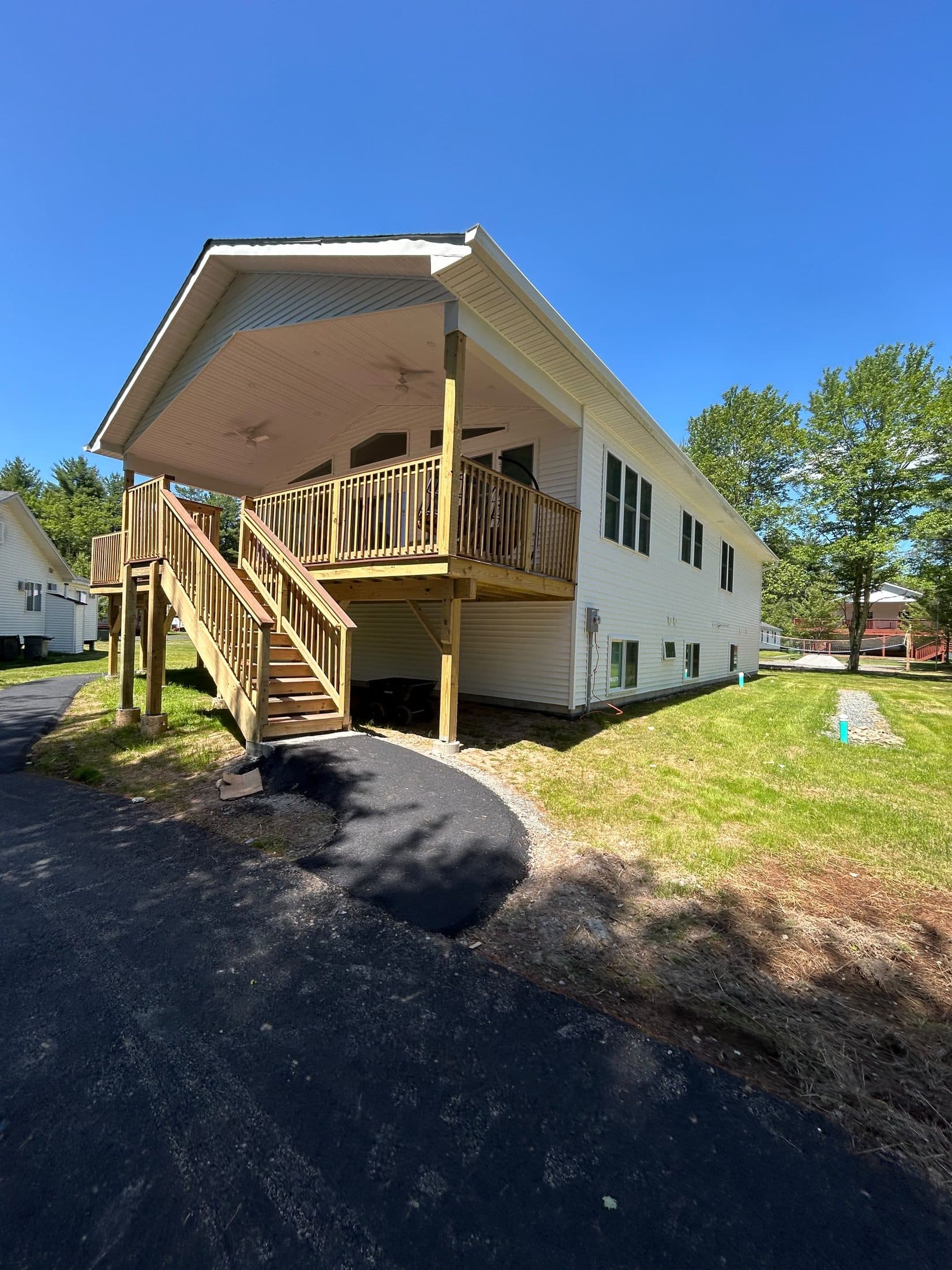 A white campus building with a newly built deck and exterior stair, standing on freshly graded ground