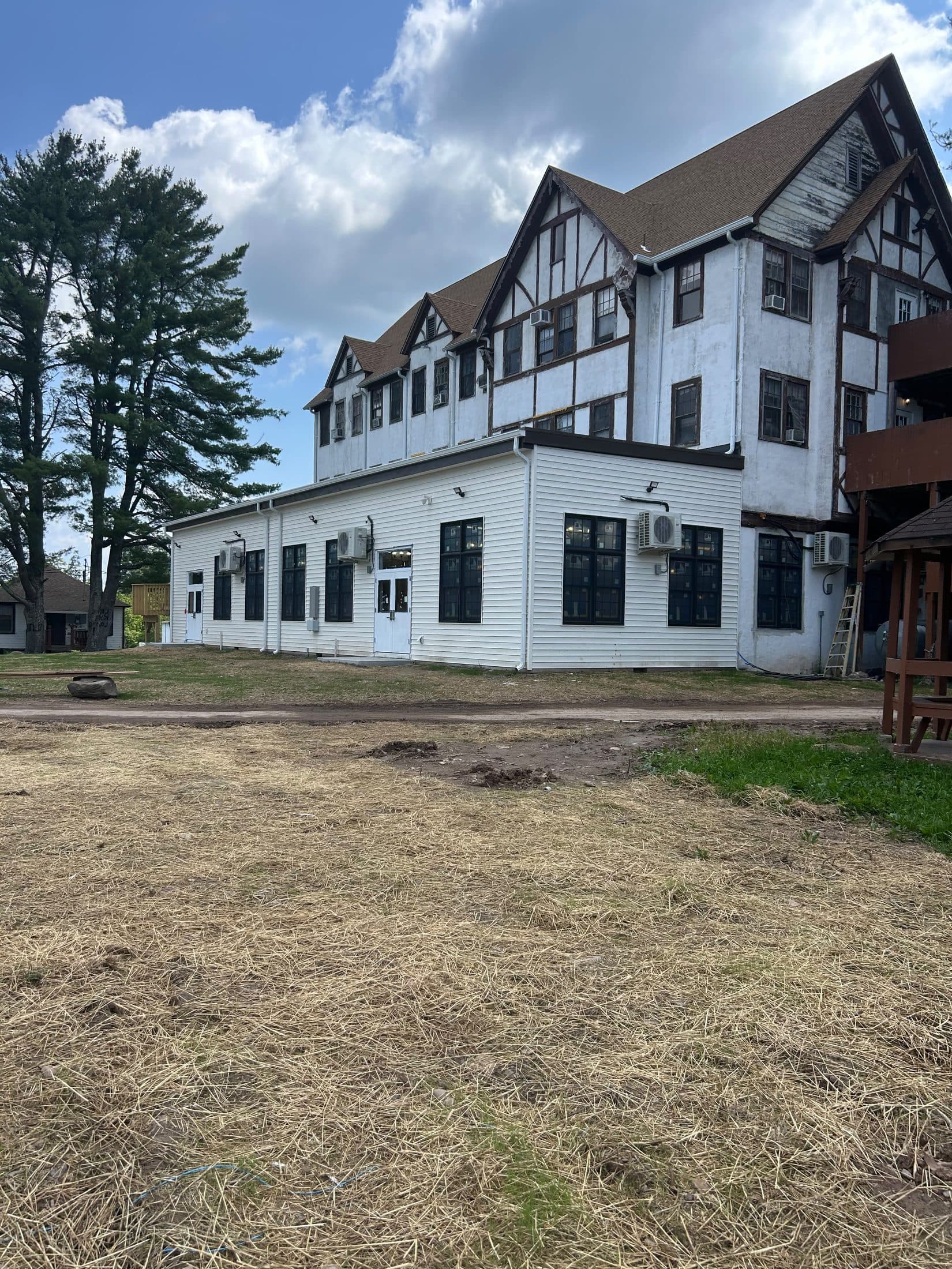 A large multi-storey building with a Tudor-framed gable end, seen across cleared ground