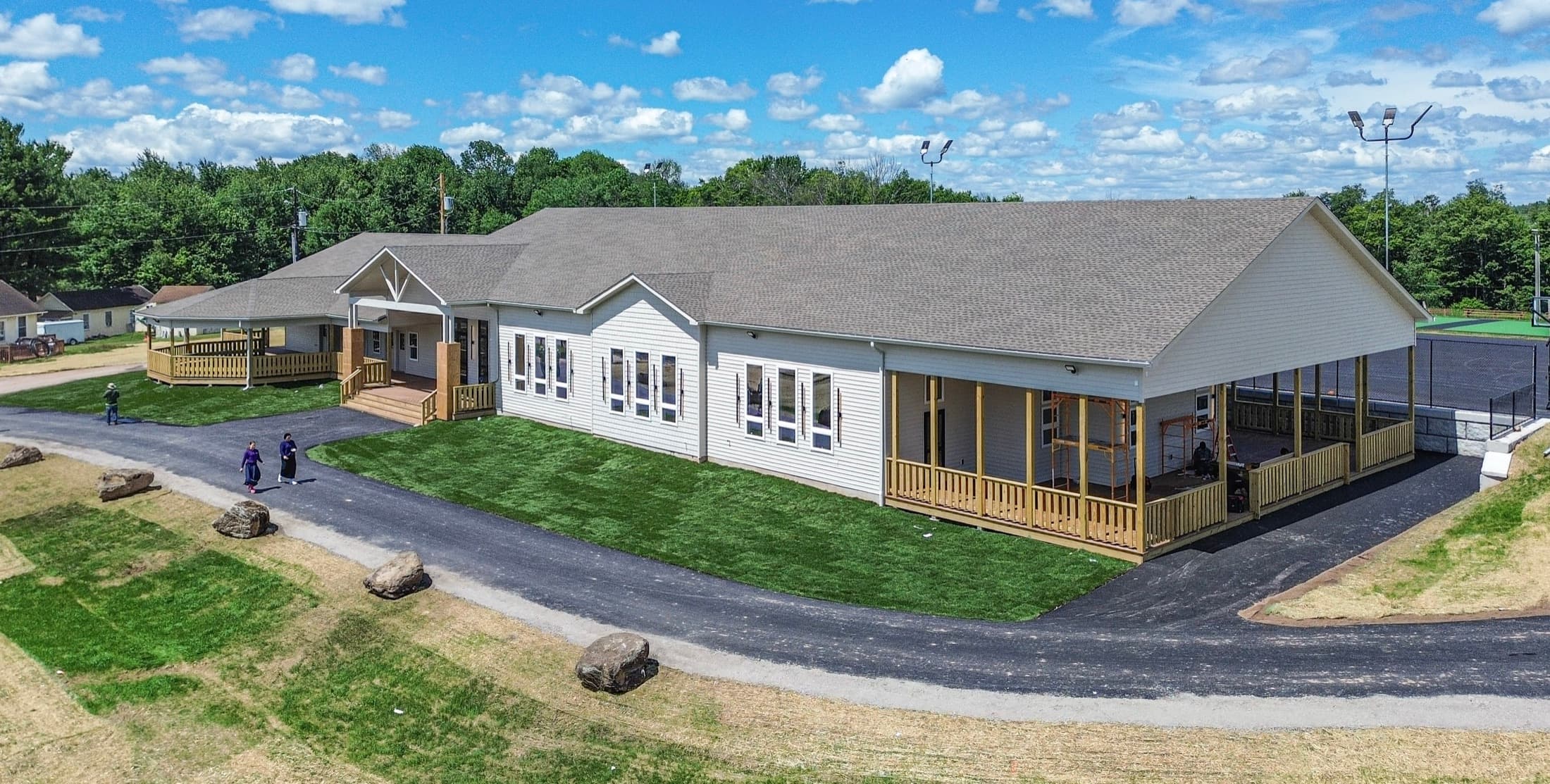Aerial view of a completed shul with a wraparound porch and a new access road
