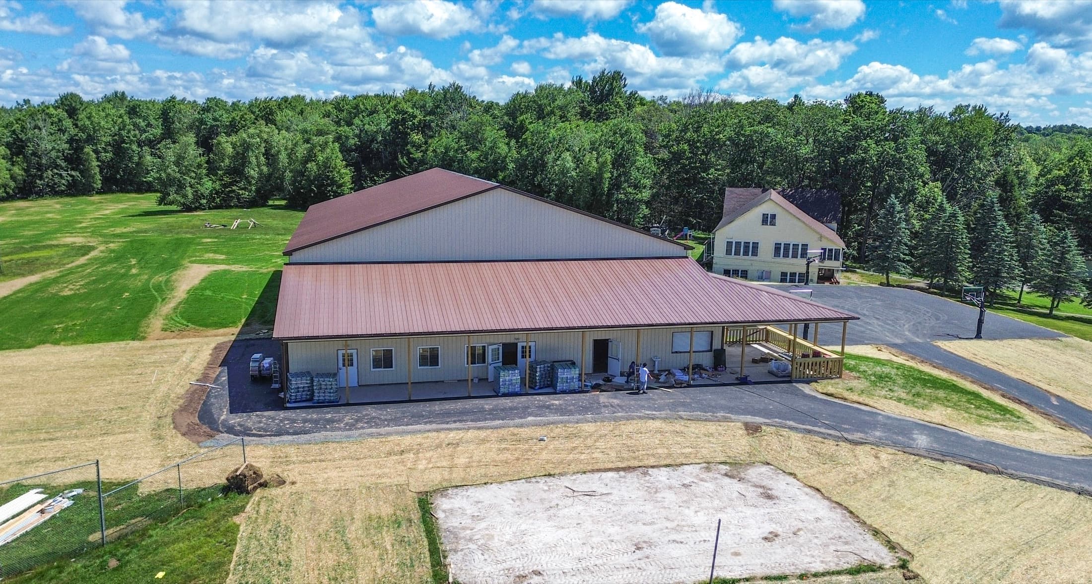 Aerial view of a main building with a covered walkway along its length, set on newly graded ground