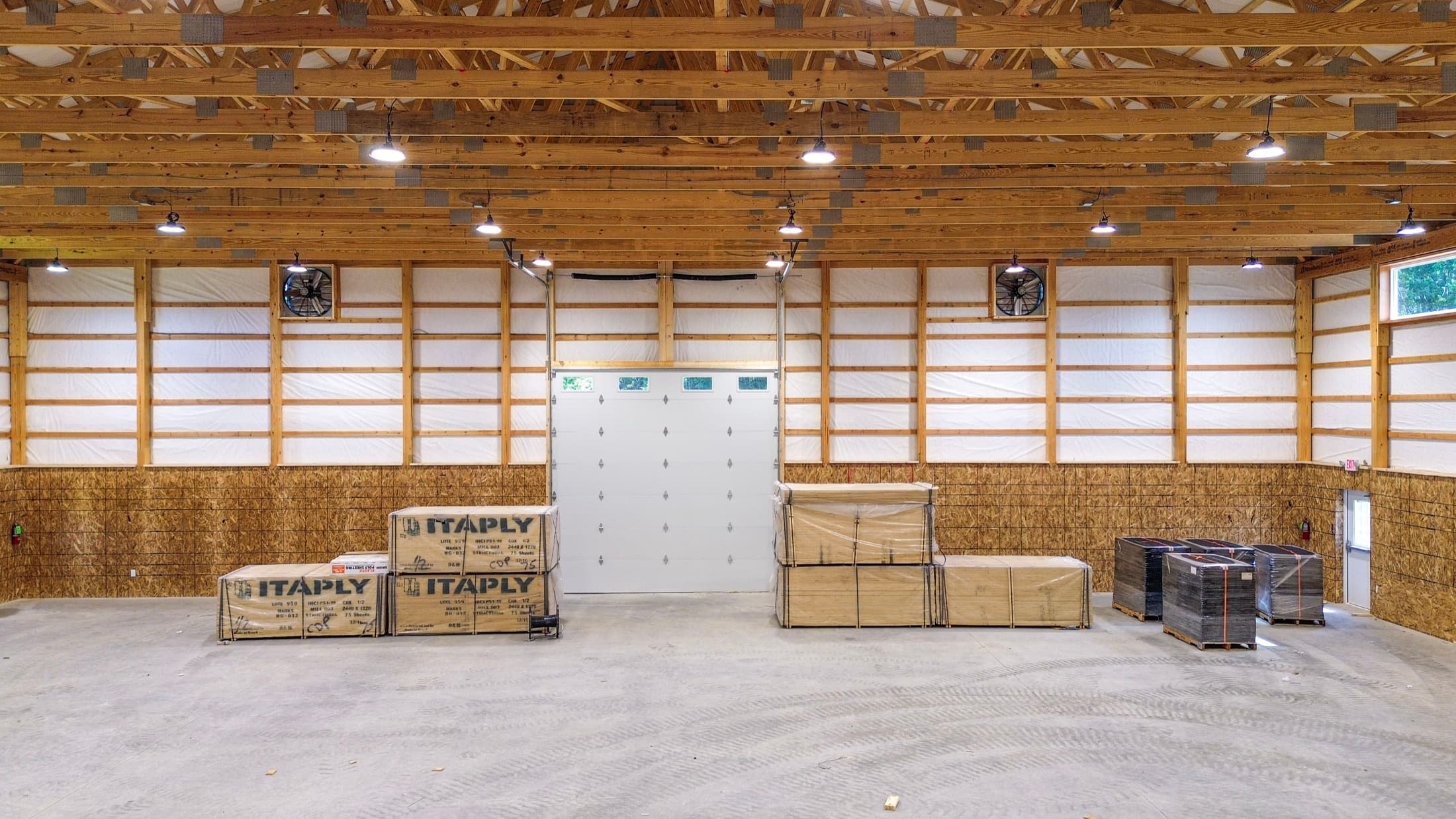 The full width of a recreation building's interior, roof trusses carrying the lighting clear of the playing volume