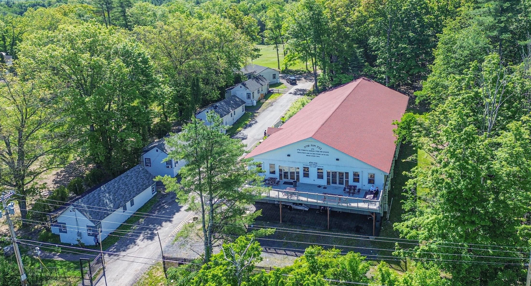 Aerial view of a camp campus, the lodge and bunk buildings set among woodland along a new access road