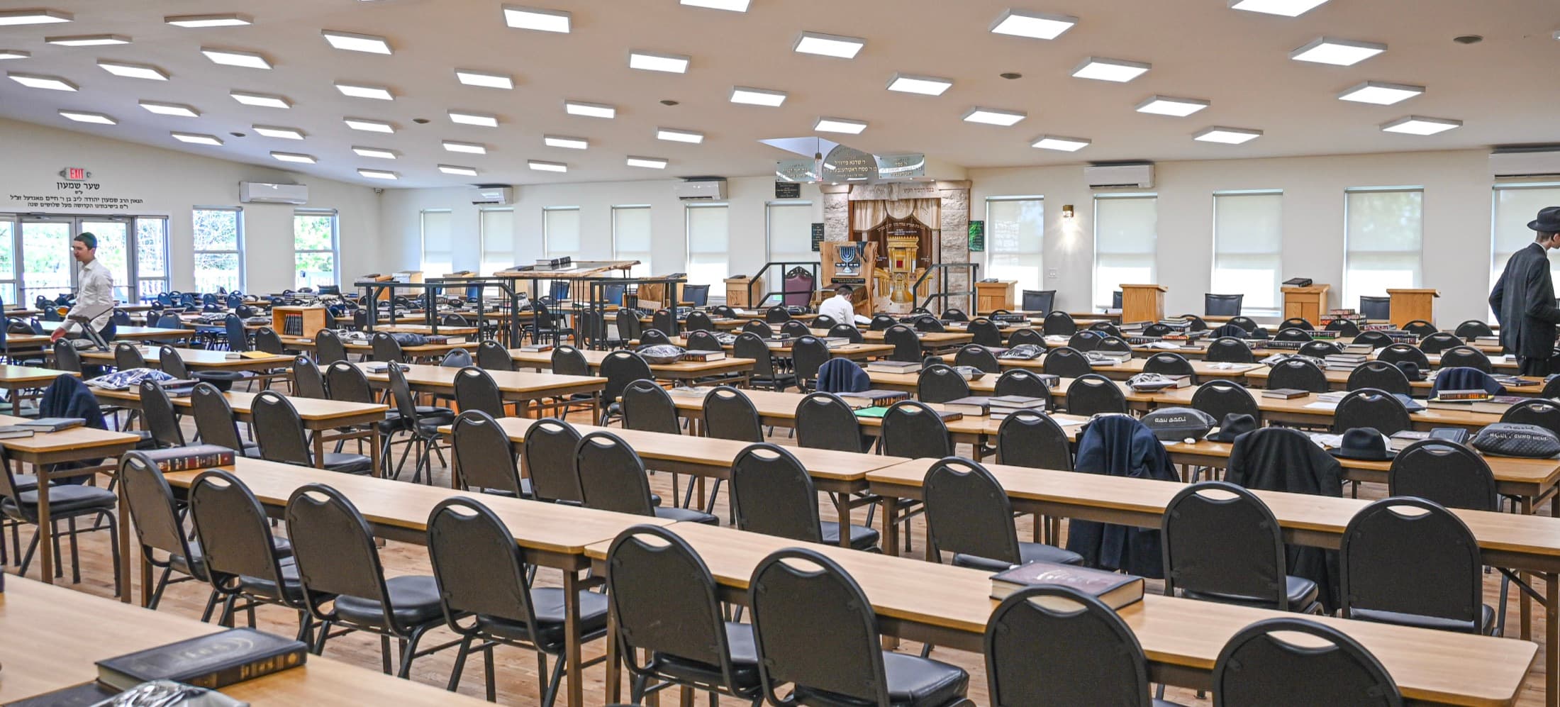 A beis medrash looking toward the front, rows of tables and chairs set out for the whole camp at once