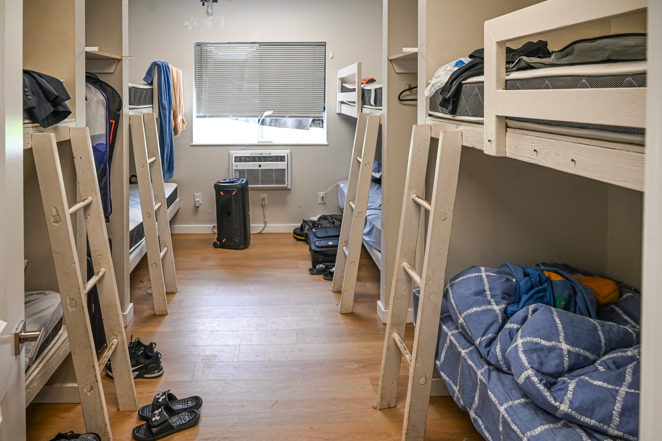 A camp bunk room with timber bunk beds, wood flooring and built-in storage along the wall