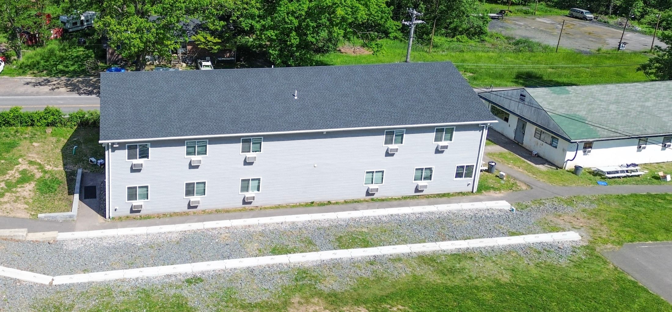 Aerial view of a two-storey dormitory building with a grey roof, on newly graded ground