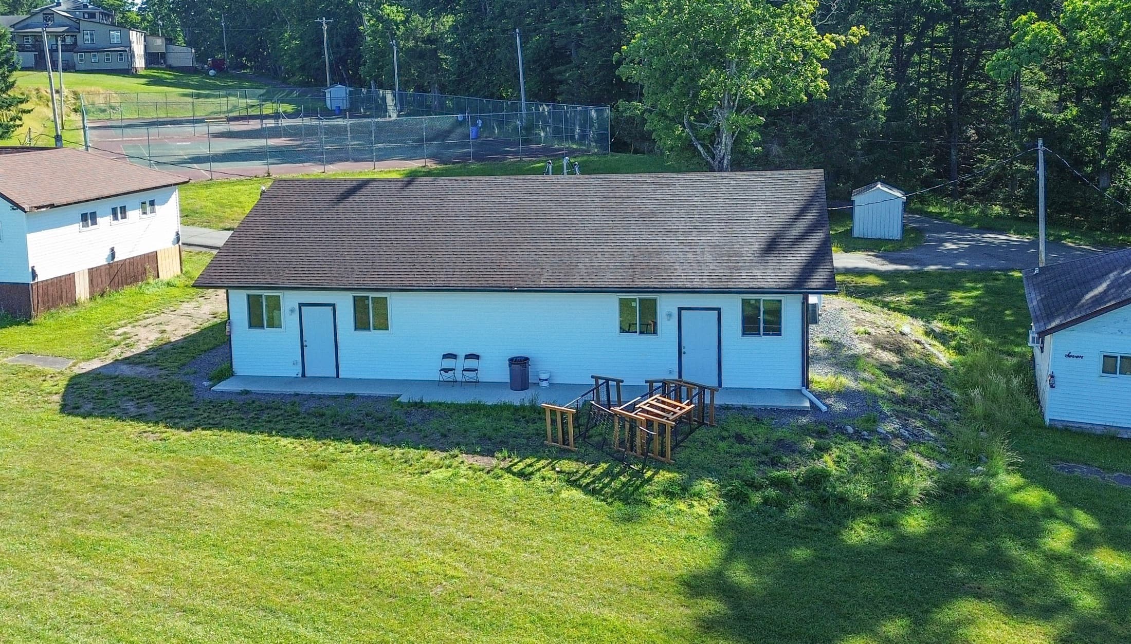 Aerial view of a single-storey bunk building with a covered entry, set on a campus lawn