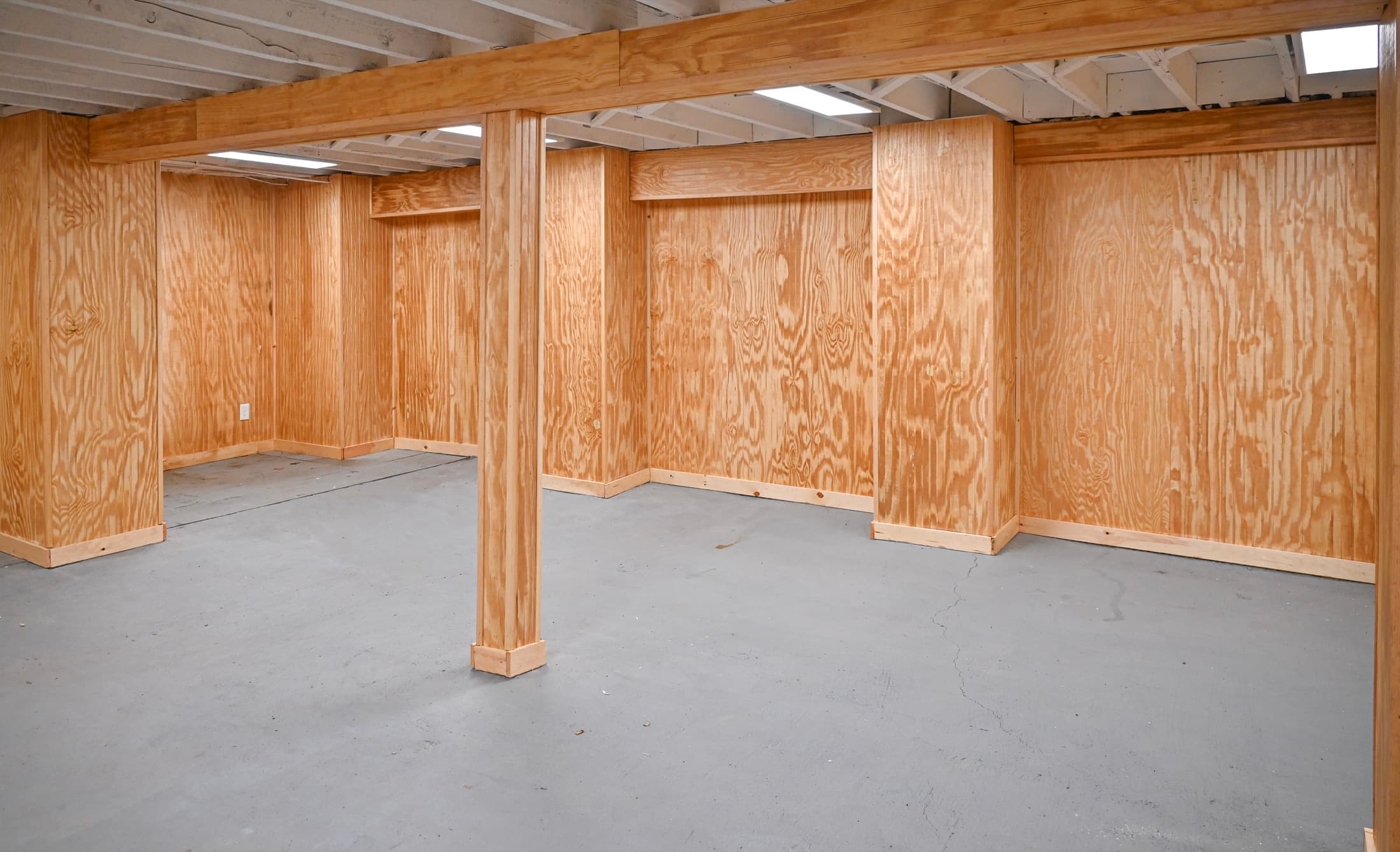 Interior framing on a ground floor — plywood-sheathed walls and posts standing on a poured slab
